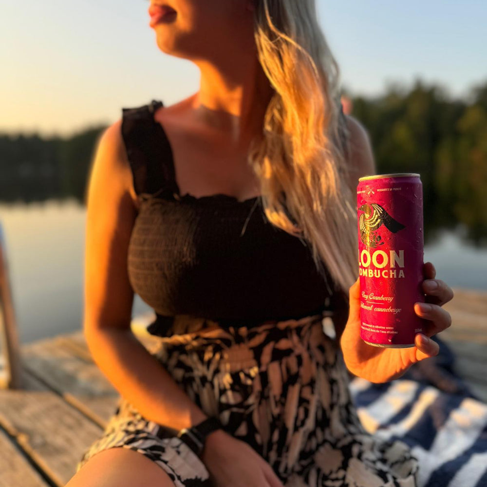 Woman holding kombucha can at sunset